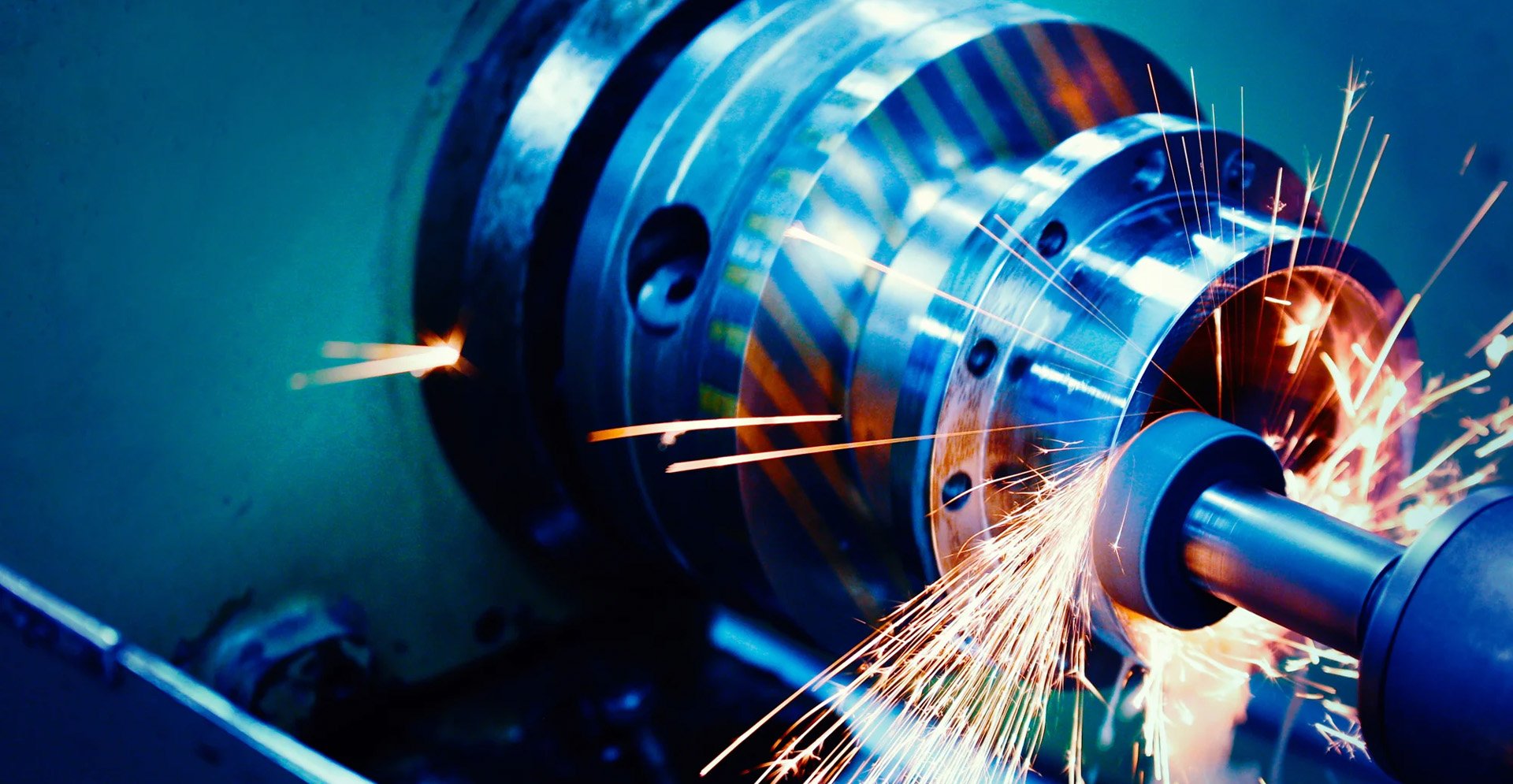 Close-up of a metalworking machine grinding a rotating component, producing bright sparks.