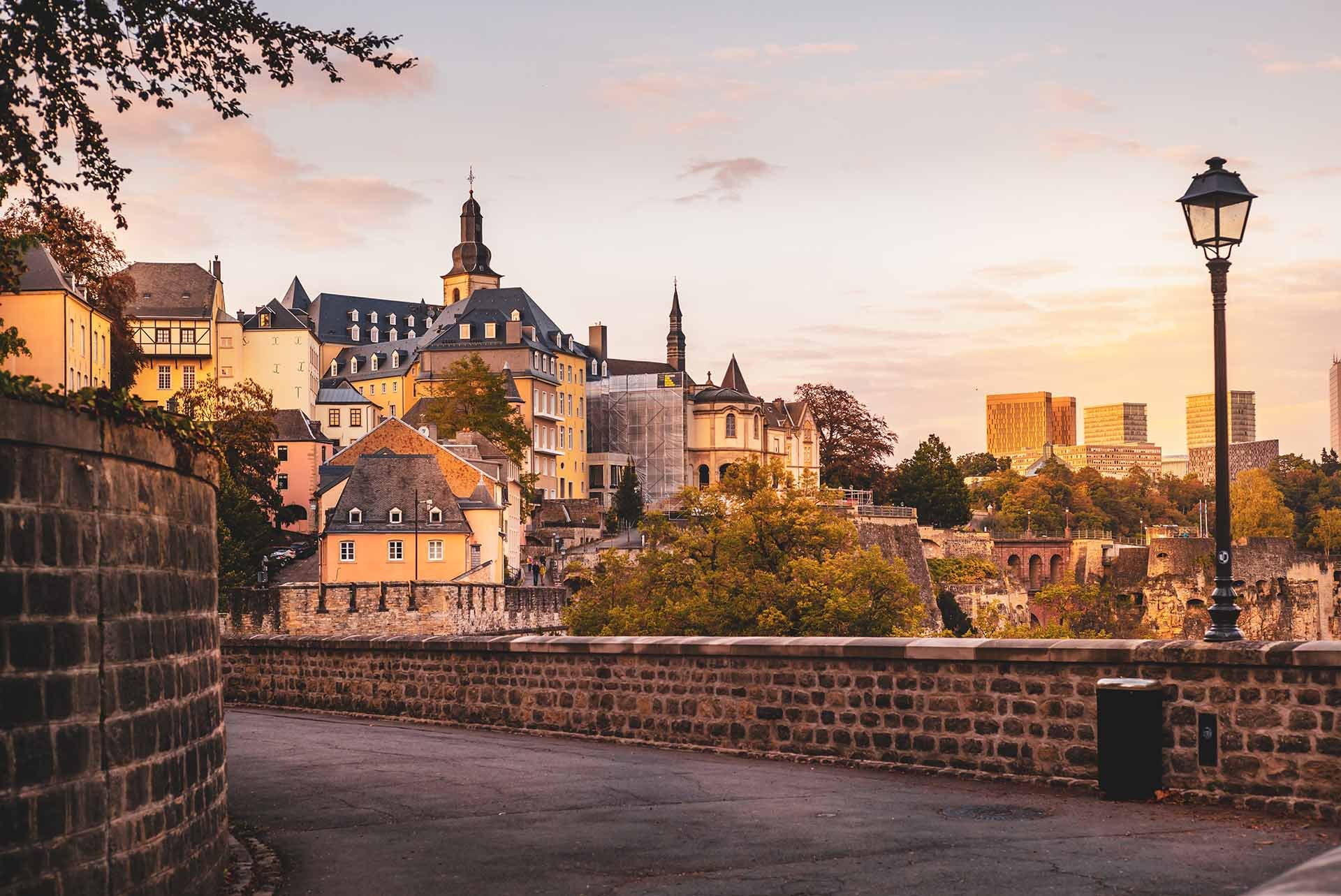 Scenic view of historic buildings and stone walls at sunset in a European city.