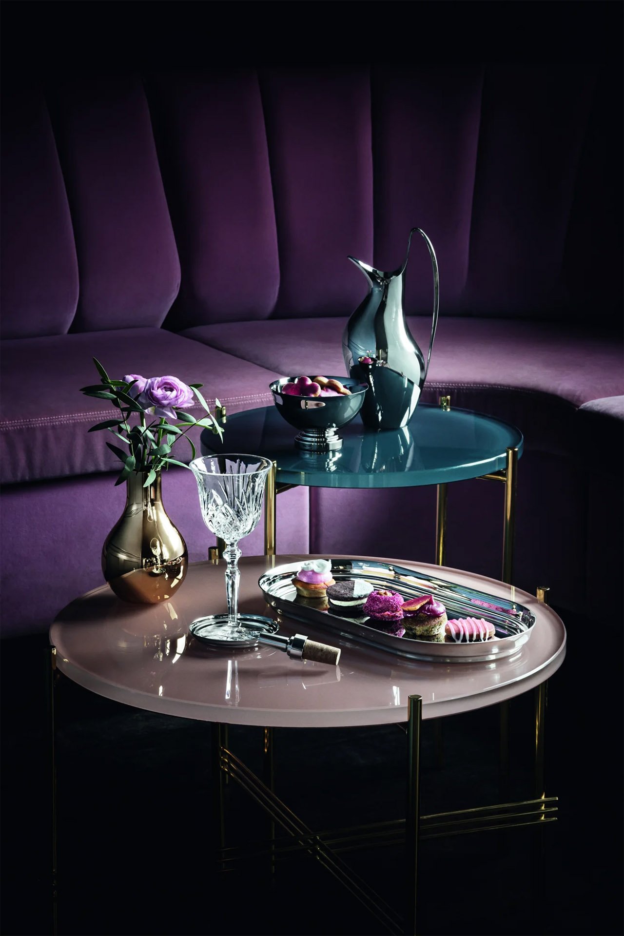 Sophisticated lounge setup with purple seating, round tables, and metallic serveware with desserts.