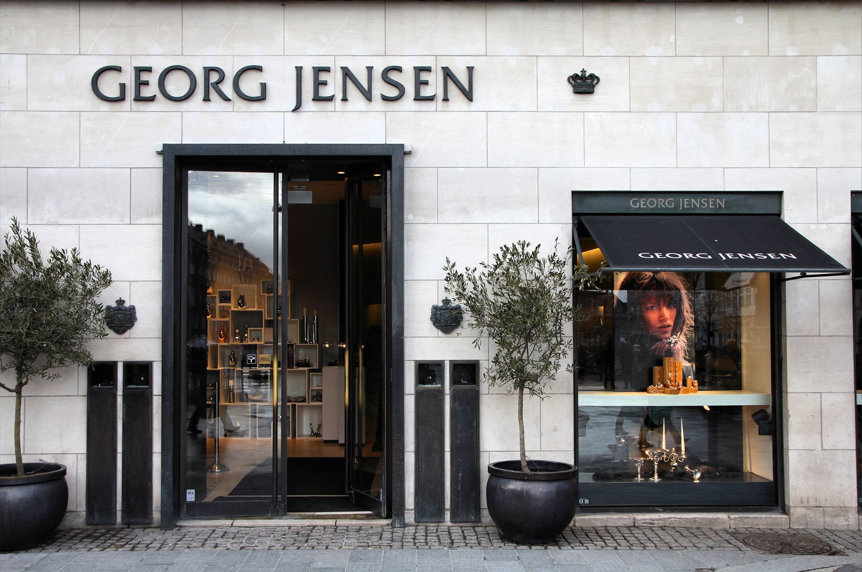 Exterior of a Georg Jensen store with large display window and brand signage above entrance.