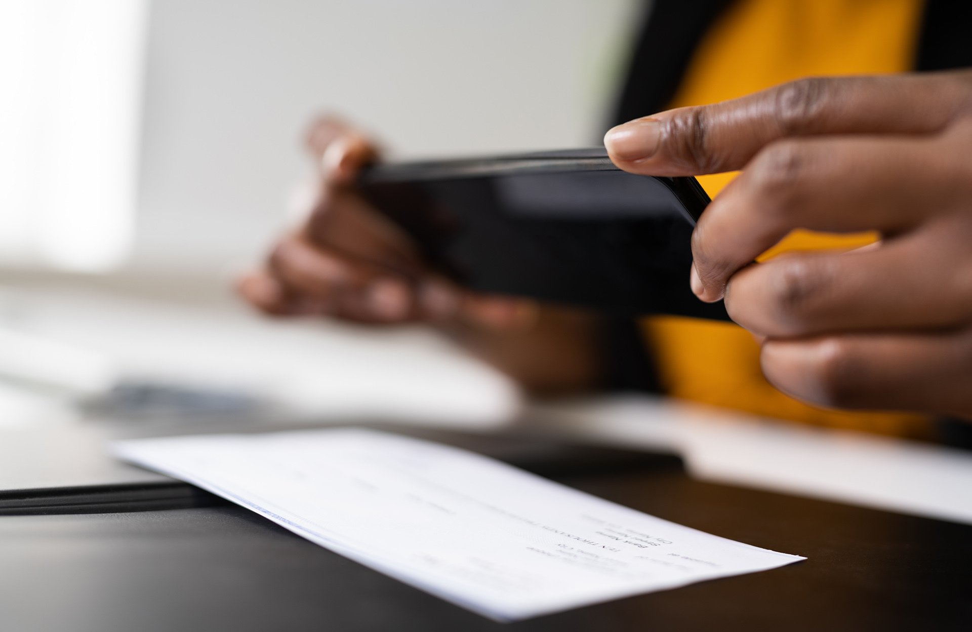 Person taking a photo of a check with a smartphone for mobile deposit.