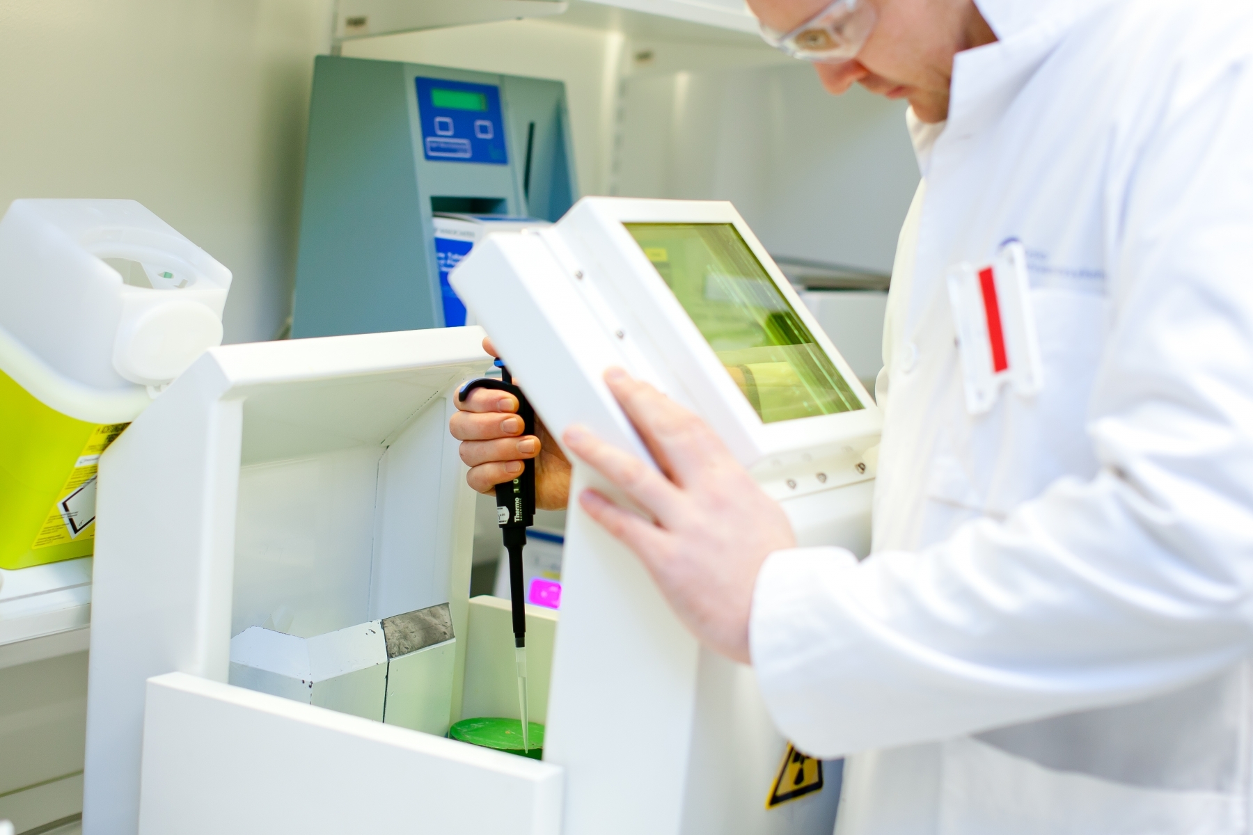 Scientist in a lab coat using laboratory equipment for medical or chemical testing.