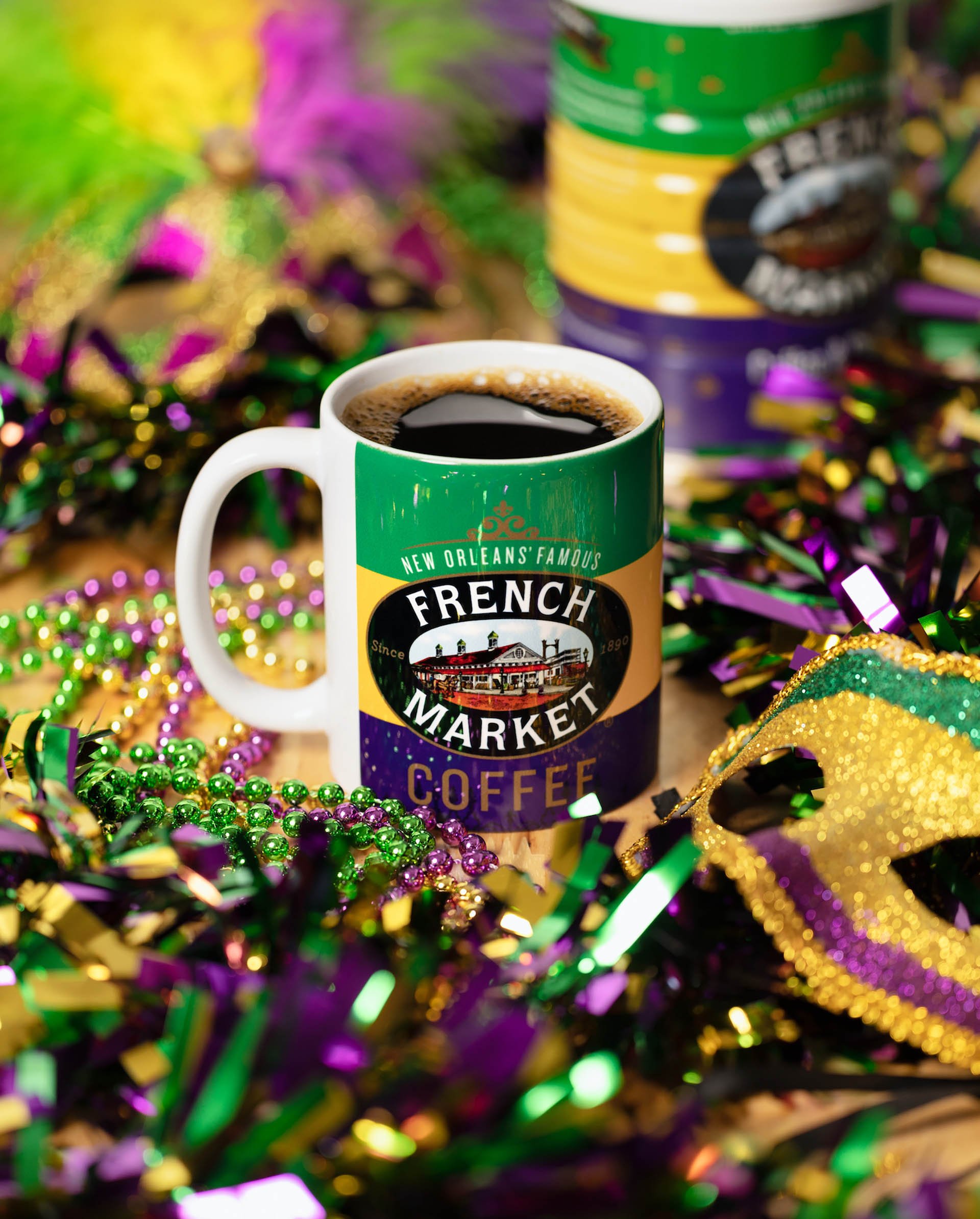 Mug of French Market coffee surrounded by Mardi Gras beads, tinsel, and a decorative mask.