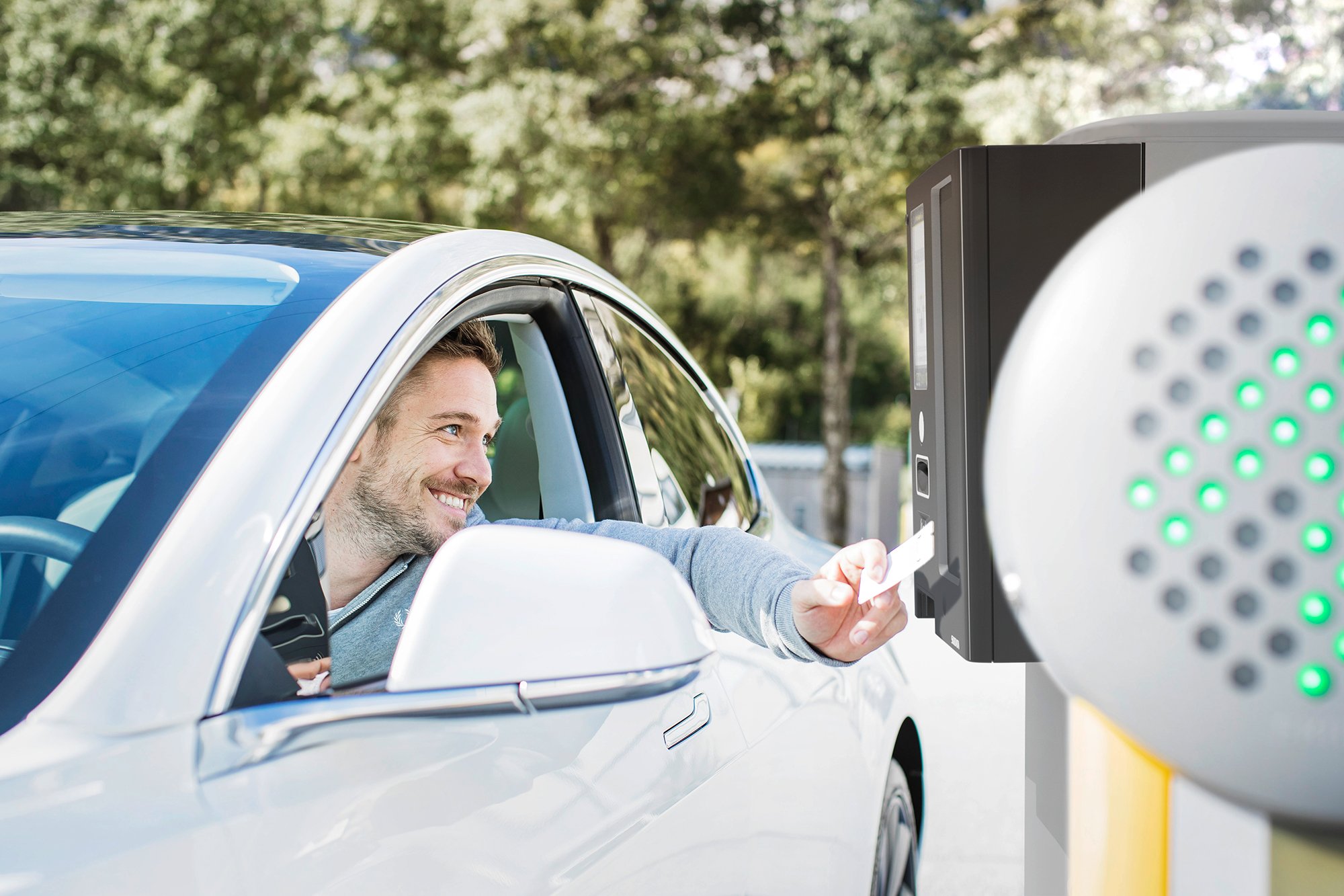 Man in a car using a ticket at an automated parking or toll booth.