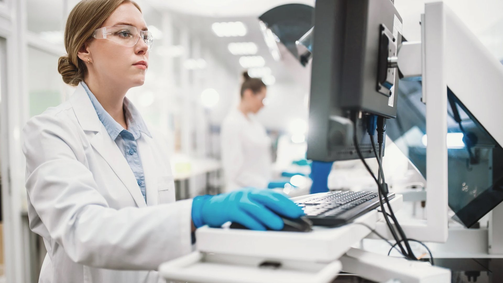 Female scientist using a computer in a modern laboratory setting.