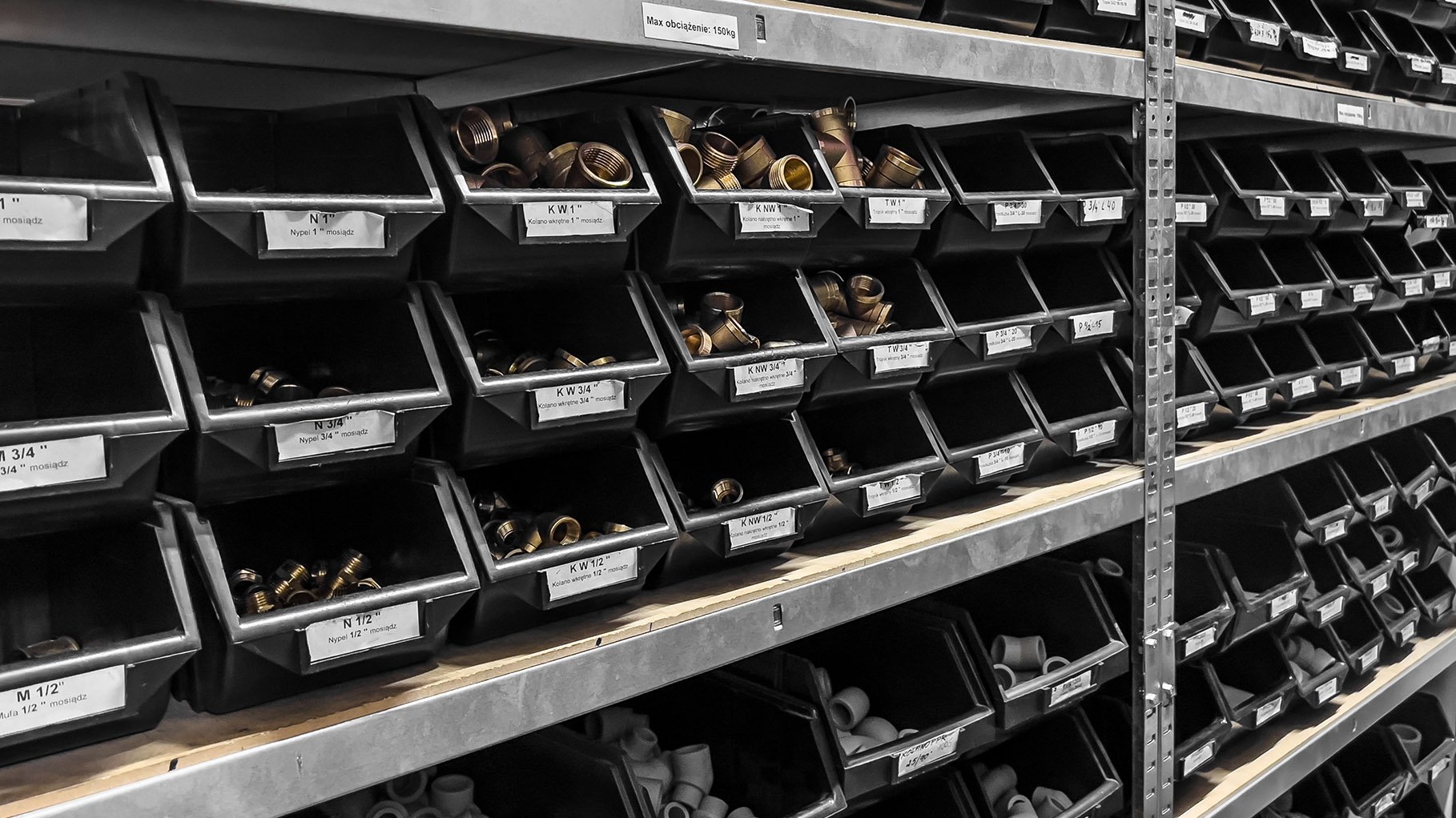 Organized shelves filled with labeled bins containing various metal plumbing fittings and hardware components.