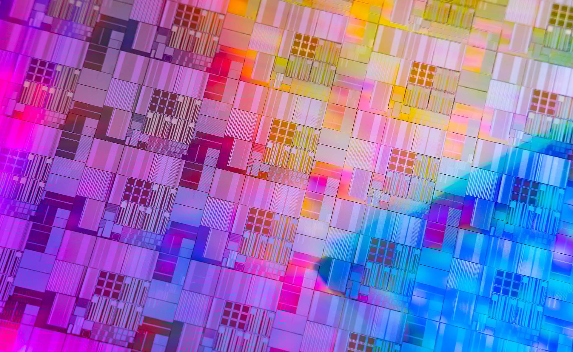 Colorful, intricate patterns on a silicon wafer chip, showcasing various textures and reflections in vibrant hues.