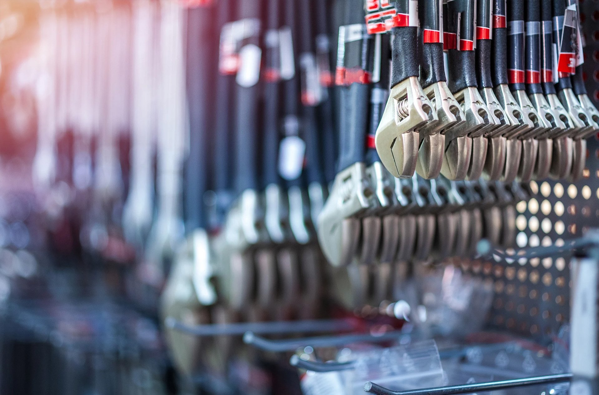 Row of adjustable wrenches hanging on display in a hardware store.