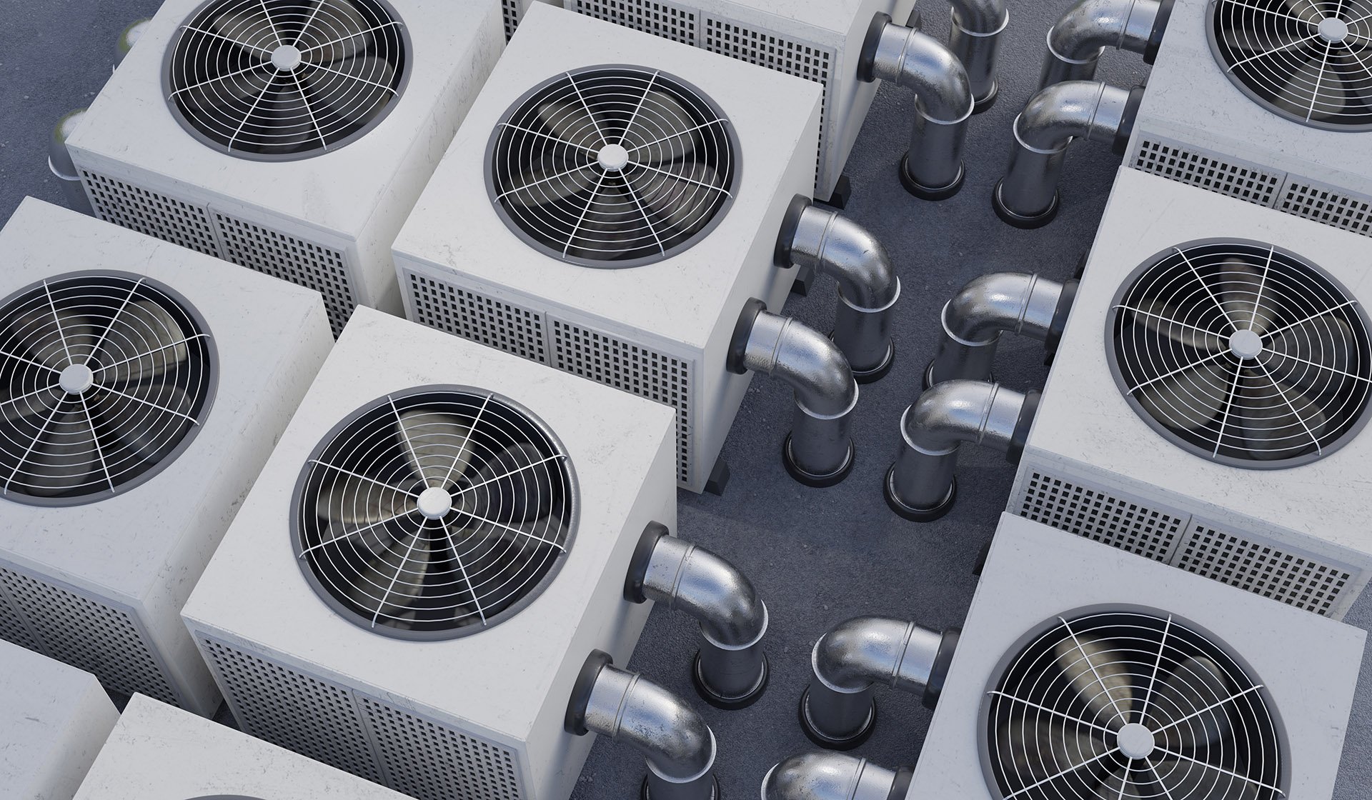 Aerial view of multiple outdoor HVAC units with metal exhaust pipes and grid-covered fan openings, arranged on a flat surface.