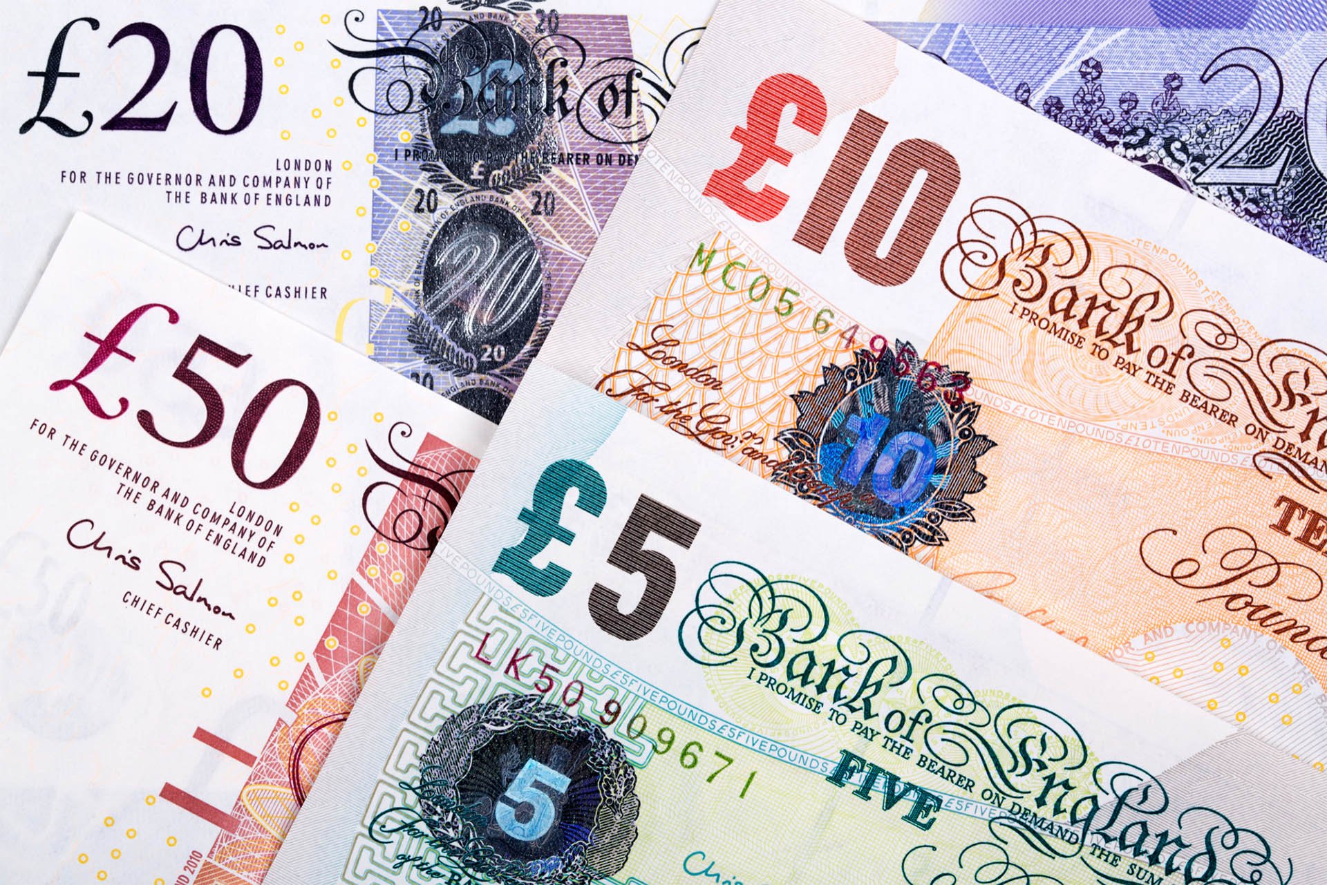 Close-up of British pound banknotes in denominations of £5, £10, £20, and £50.