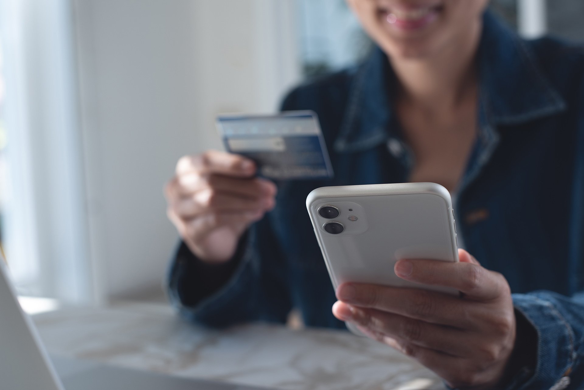 Person holding a smartphone and credit card while making an online purchase.