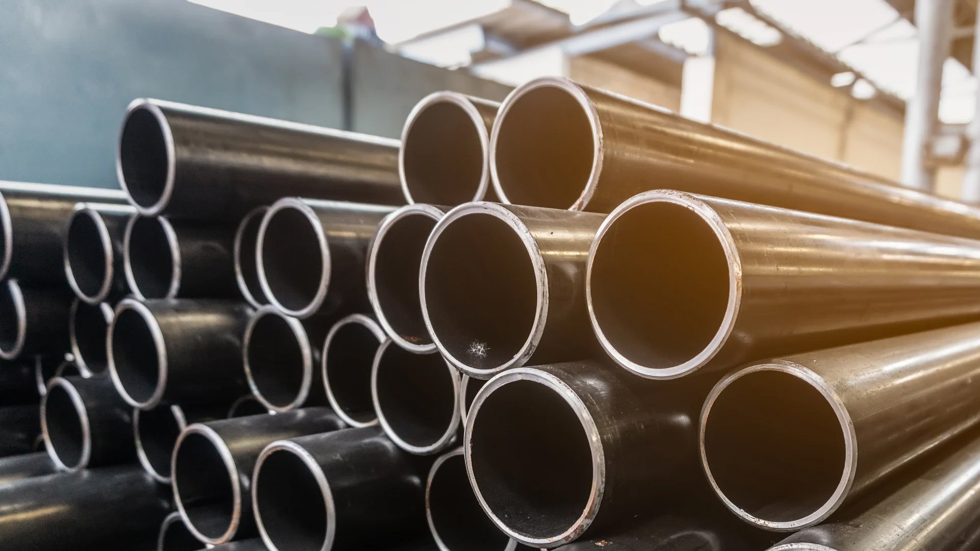 Stacked metal pipes in a warehouse or industrial facility.