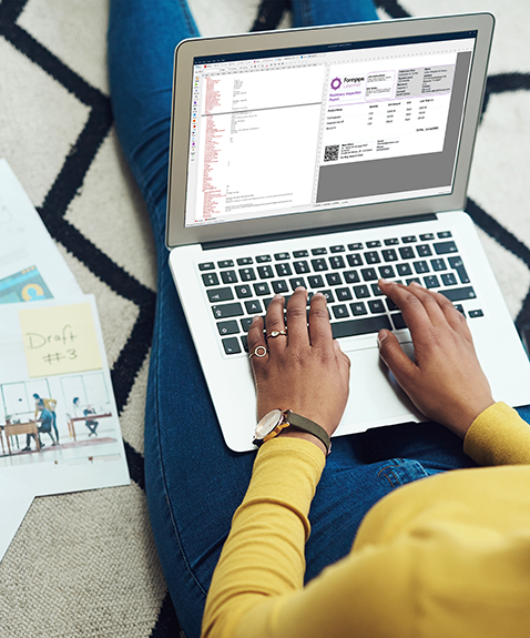 Woman sitting on a patterned rug, working on a laptop. Papers with graphs and charts lie nearby.