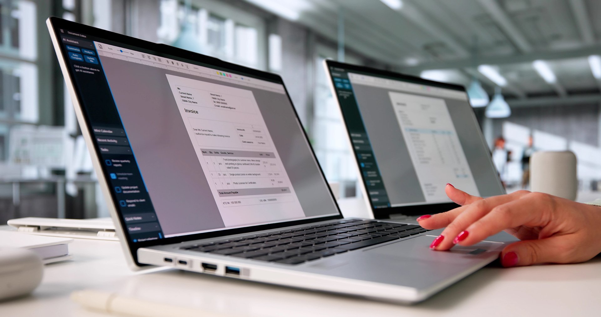 A hand with red nail polish hovers over a laptop keyboard displaying an invoice, next to another screen showing a document.
